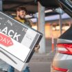 Black Friday Fernseher: Ein Mann hievt einen Fernseher in sein Auto