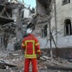 Un sauveteur ukrainien se tient à côté d'un immeuble résidentiel partiellement détruit par une attaque de missiles à Kharkiv, le 17 janvier 2024.