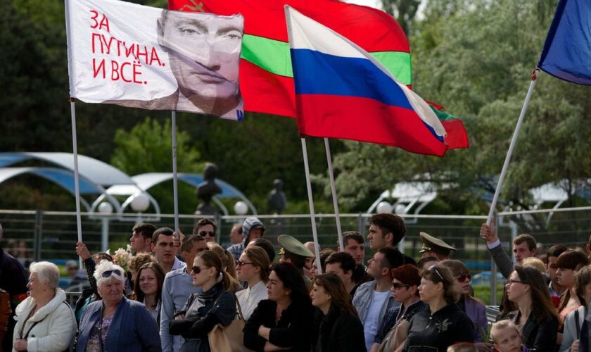 Des gens portent un drapeau russe (C) et un drapeau avec un portrait du président russe Vladimir Poutine sur lequel on peut lire "Nous sommes pour Poutine !" à Tiraspol, la principale ville de la région séparatiste de Transnistrie en Moldavie, le 9 mai 2014.