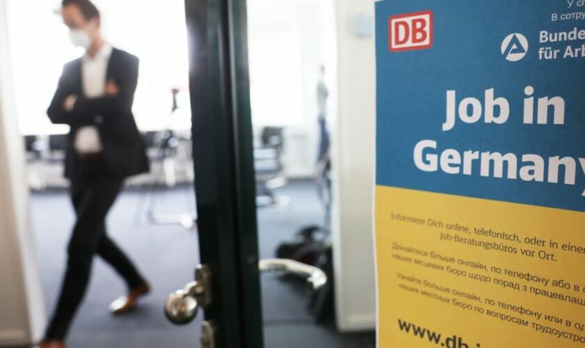 Ein Mann geht in einem Jobberatungszentrum an einem Plakat mit der Aufschrift "Job in Germany" vorbei. Foto: Oliver Berg/dpa/Arc
