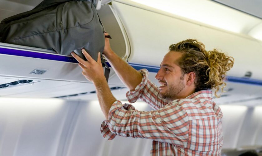 Ein Mann verstaut sein Handgepäck im Flugzeug