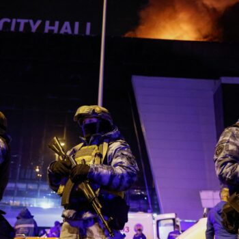 Russian authorities stand guard near the burning Crocus City Hall concert venue. Pic: Reuters