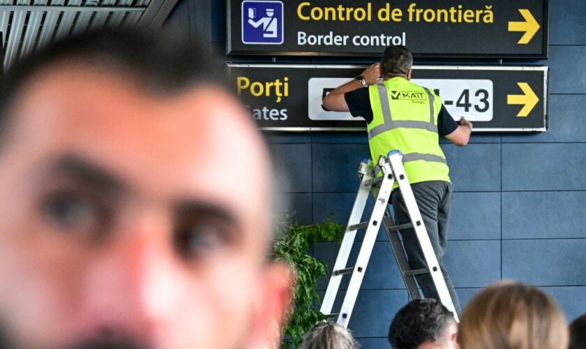 A Romanian worker changes the signs to lead passengers of the non-Schengen flights toward newly installed border control points inside the Henri Coanda International Airport in Otopeni, Romania, on March 28, 2024. Romania and Bulgaria will join on Sunday, March 31, 2024 Europe's passport- and visa-free Schengen Area, applying only to travelers arriving by air and sea. (Photo by Daniel MIHAILESCU / AFP)