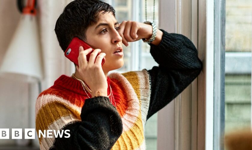 A woman at home on hold on her mobile phone