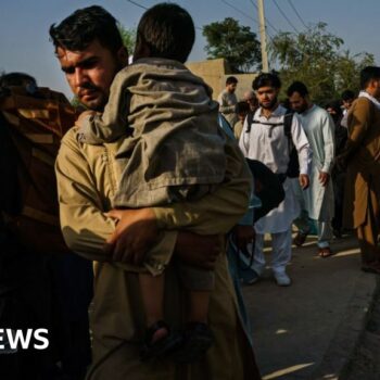 Afghans make their way the road to the military entrance of the airport for evacuations, in Kabul, Afghanistan
