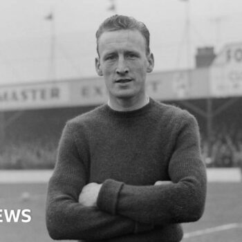 Black and white photo of Ron Baynham with short hair on a football pitch