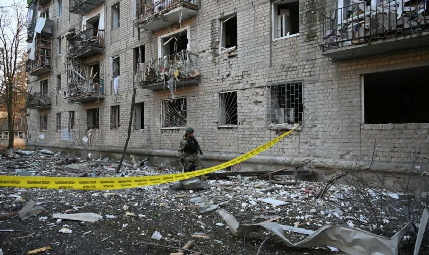Un secouriste travaille devant un immeuble résidentiel endommagé par les frappes russes à Kharkiv, le 27 mars 2024