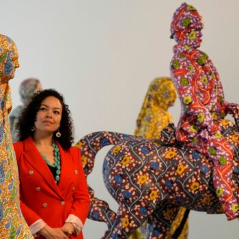 A visitor looks at sculptures made of fibreglass and handpainted by Artist Yinka Shonibare during a photocell for his Suspended States exhibition at Serpentine South in London, Thursday, April 11, 2024. Serpentine presents a solo exhibition of new and recent works by British Nigerian artist Yinka Shonibare. The first solo exhibition of Shonibare's work for over 20 years in a London public institution, will be presented at Serpentine South from April 12 to September 1 2024.(AP Photo/Frank Augstein)