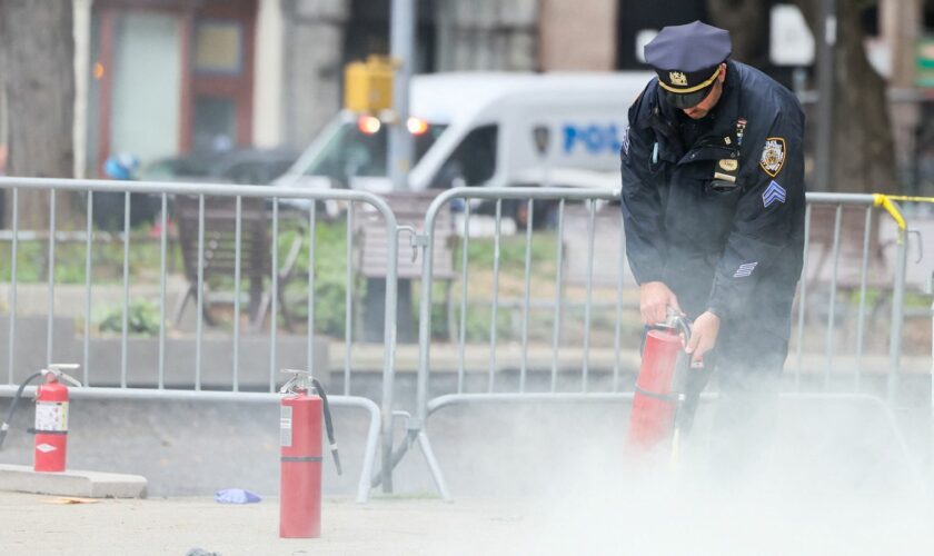 A police officer uses a fire extinguisher as emergency personnel respond to the scene where a person was covered in flames. Pic: Reuters