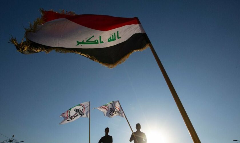 Photo prise le 17 octobre 2020 de partisans du Hachd al-Chaabi, paramilitaires pro-Iran intégrés à l'Etat irakien, brandissant le drapeau du Hachd à Basra, dans le sud de l'Irak