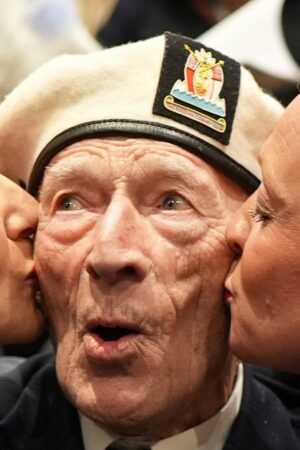 D-Day veteran Alec Penstone, 98, who served with the Royal Navy, receives a kiss from the D-Day Darlings. Pic: PA