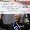 Cheng "Charlie" Saephan holds display check above his head after speaking during a news conference where it was revealed that he was one of the winners of the $1.3 billion Powerball jackpot at the Oregon Lottery headquarters on Monday, April 29, 2024, in Salem, Ore. (AP Photo/Jenny Kane)
