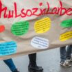 Teilnehmer einer Demonstration halten ein Plakat mit der Aufschrift "Schulsozialarbeit" hoch. Foto: Jens Büttner/dpa-Zentralbild