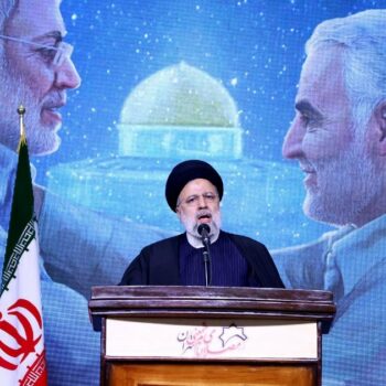 Le président iranien Ebrahim Raïssi prononce un discours en hommage au général Qassem Soleimani (à droite sur l'écran derrière lui), lors d'une cérémonie marquant le quatrième anniversaire de sa mort, le 3 janvier 2024 à Téhéran.
