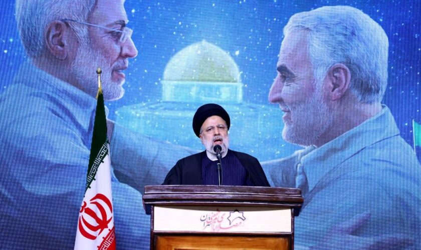 Le président iranien Ebrahim Raïssi prononce un discours en hommage au général Qassem Soleimani (à droite sur l'écran derrière lui), lors d'une cérémonie marquant le quatrième anniversaire de sa mort, le 3 janvier 2024 à Téhéran.