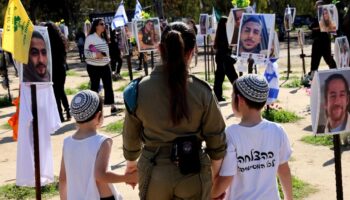 Une militaire israélienne et deux enfants visitent un mémorial pour les victimes de l'attaque du Hamas le 7 octobre contre un festival de musique, près du kibboutz Reim dans le sud d'Israël, le 7 février 2024