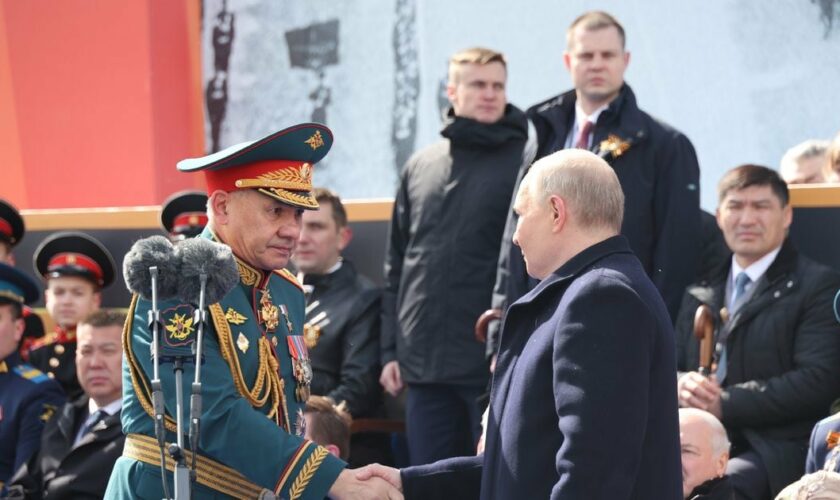 Le président russe Vladimir Poutine (d) serre la main du ministre de la Défense Sergueï Choïgou lors du défilé militaire du Jour de la Victoire sur l'Allemagne nazie, le 9 mai 2024 à Moscou