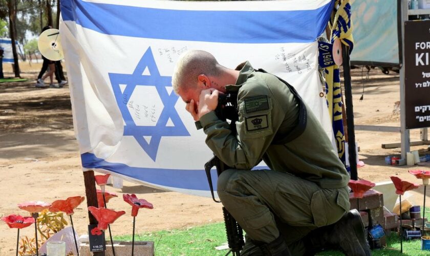 Un soldat israélien se recueille devant des photos de personnes capturées ou tuées par des militants du Hamas lors du festival de musique Supernova le 7 octobre, sur le site où l'attaque meurtrière a eu lieu, près du kibboutz Reim, dans le sud d'Israël,