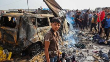 Des personnes se rassemblent sur le site d'une frappe nocturne ayant mis le feu à des tentes occupées par des Palestiniens déplacés dans un camp à Rafah, dans la bande de Gaza, le 27 mai 2024