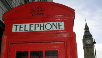 Eine rote Telefonzelle steht vor dem Big Ben in London