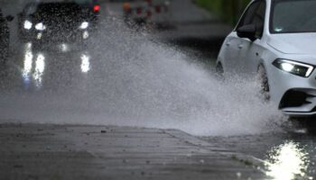 Ein Auto fährt durch eine große Wasserlache. Foto: Federico Gambarini/dpa