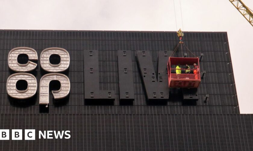 Construction workers outside the Arena in front of an unfinished Co-Op Live sign