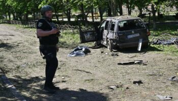 Un policier ukrainien près d'une voiture détruite par une frappe russe à Zlotchiv, dans la région de Kharkiv, le 1er mai 2024