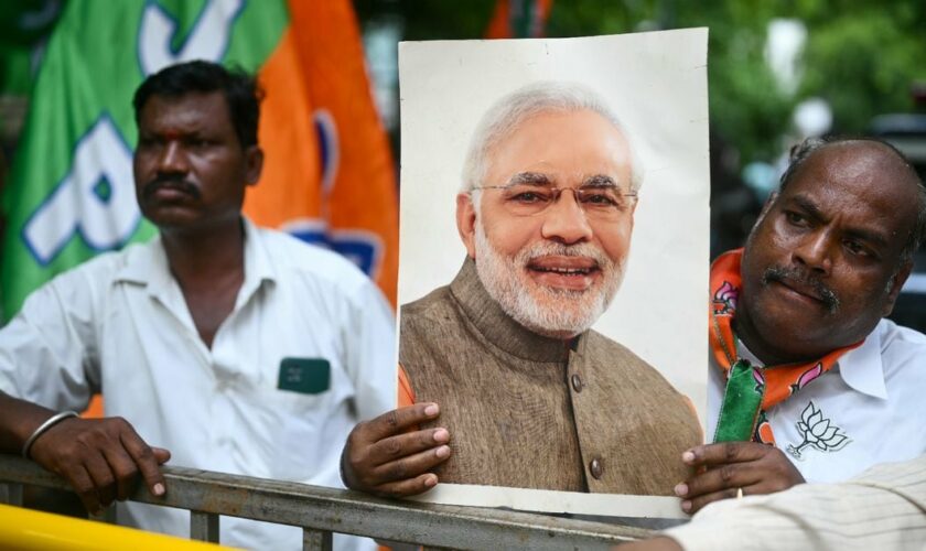 Un partisan de Narendra Modi, Premier ministre indien et chef du parti Bharatiya Janata (BJP), montre son portrait devant un bureau de vote à Bangalore, le 4 juin 2024
