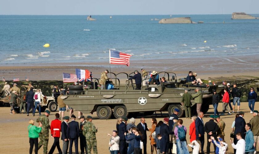 Des visiteurs près de camions amphibies DUKW sur la plage d'Arromanches-les-Bains, le 5 juin 2024, dans le cadre des commémorations du "Jour J " marquant le 80e anniversaire du débarquement allié de la Seconde Guerre mondiale en Normandie