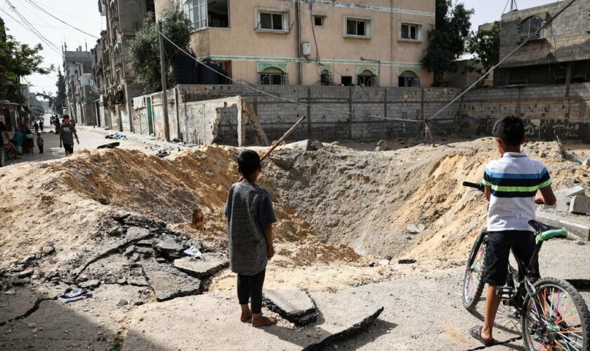 Des enfants devant un cratère causé par un bombardement israélien à Rafah, dans le sud de la bande de Gaza, le 18 mai 2024