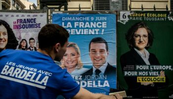 Un bénévole du RN colle une affiche de campagne de Jordan Bardella, président du parti et tête de liste aux européennes, le 6 mai 2024 à Lyon