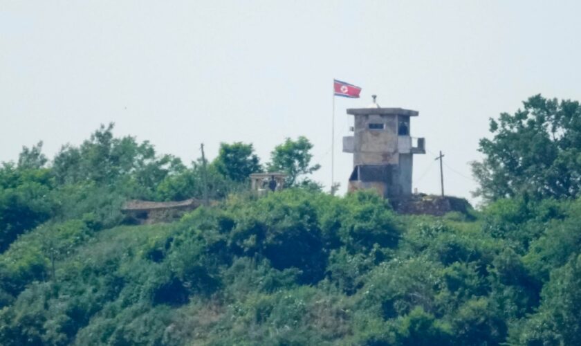 North Korean soldiers stand near their military guard post as a North Korean flag flutters in the wind, seen from Paju, South Korea, Sunday, June 9, 2024. South Korean soldiers fired warning shots after North Korean troops briefly violated the tense border earlier this week, South Korea's military said Tuesday, as the rivals are embroiled in Cold War-style campaigns like balloon launches and propaganda broadcasts. (AP Photo/Lee Jin-man)