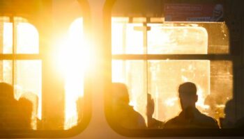 Fahrgäste sitzen bei Sonnenaufgang in einer Stadtbahn. Foto: Julian Stratenschulte/dpa/Symbolbild