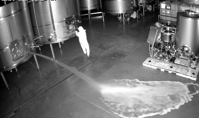 Eine Überwachungskamera-Aufnahme zeigt eine Person, die einen Weintank öffnet