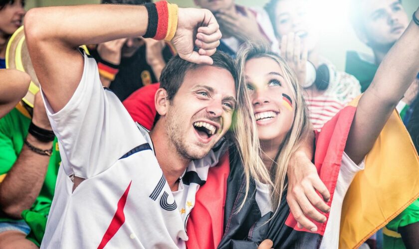 Geschenkideen für Fußballfans: Deutschland-Anhänger jubeln mit Trikot und Fahne