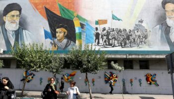 Des Iraniennes marchent dans une rue de Téhéran devant une fresque murale où figurent le guide suprême iranien Ali Khamenei (G), et le fondateur de la République islamique d'Iran, l'ayatollah Khomeiny (D), le 6 juillet 2024 au lendemain de l'élection présidentielle