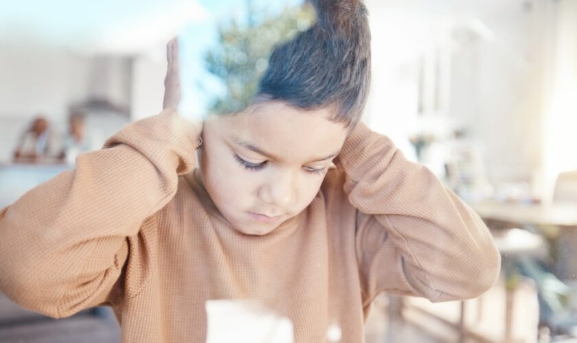 Sad, home and boy with hands on ears for depression, fear and scared of conflict with family by window. Child psychology, autism and depressed, anxiety and upset kid in living room for mental health