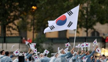 Seoyeong Kim et Sanghyeok Woo, porte-drapeaux de l'équipe de la République de Corée, sont vus en train d'agiter leur drapeau le long de la Seine lors de la cérémonie d'ouverture des Jeux Olympiques Paris 2024, le 26 juillet 2024 à Paris, France.