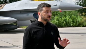 Le président ukrainien Volodymyr Zelensky devant un chasseur F-16 lors d'une cérémonie dans un lieu tenu secret en Ukraine, le 4 août 2024