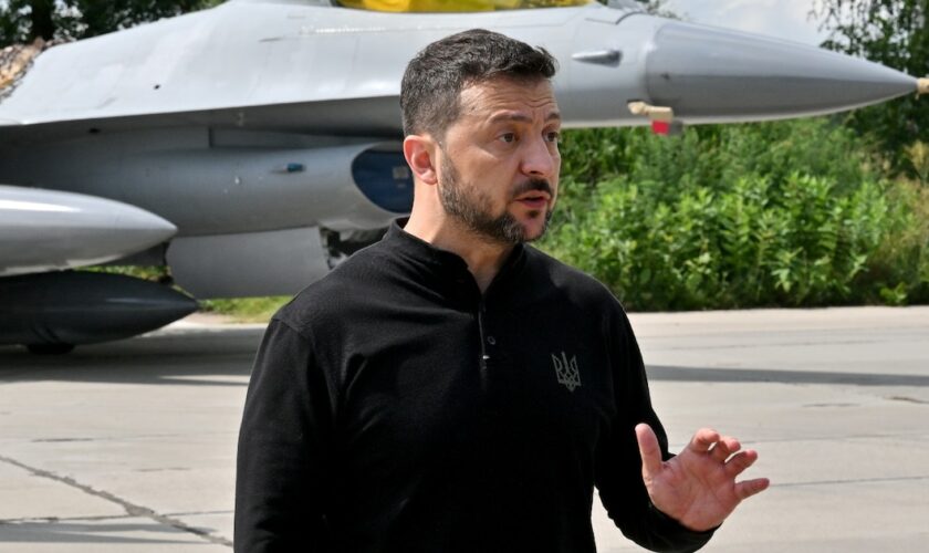 Le président ukrainien Volodymyr Zelensky devant un chasseur F-16 lors d'une cérémonie dans un lieu tenu secret en Ukraine, le 4 août 2024