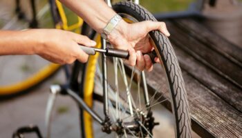 Mini-Fahrradpumpen im Vergleich: Mann pumpt Hinterrad mit Minipumpe auf