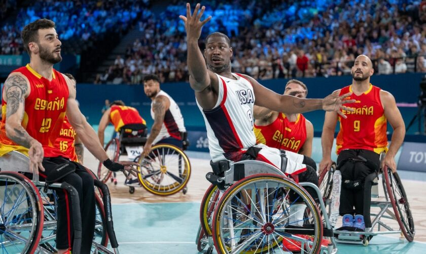 L'Américain Brian Bell (c) passe le ballon sous le regard de L'Espagnol Manuel Lorenzo (g) pendant le tour préliminaire du groupe B du match de basket-ball en fauteuil roulant entre les États-Unis et l'Espagne pendant les Jeux paralympiques de Paris 2024 à Paris, le 29 août 2024