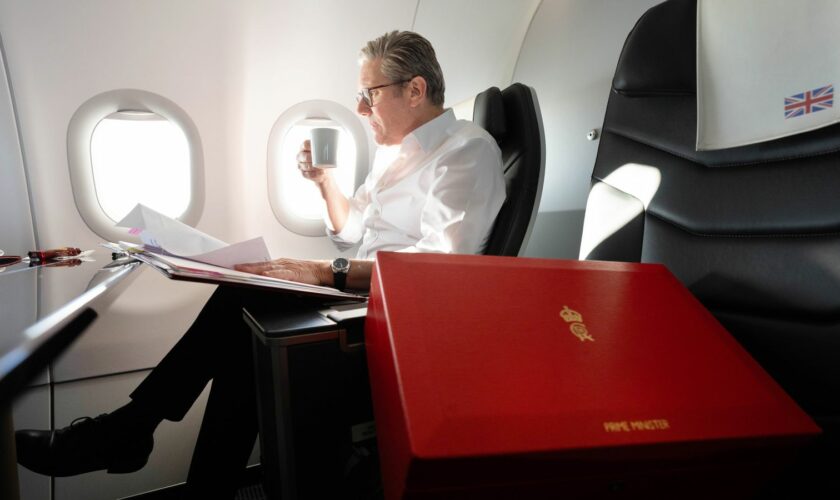 Starmer works on the plane as he flies to Washington DC. Pic: PA