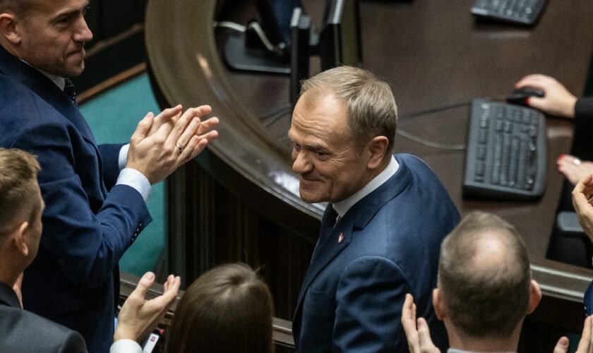 Le chef élu du nouveau gouvernement polonais Donald Tusk (c) applaudi après son discours au Parlement, le 12 décembre 2023 à Varsovie