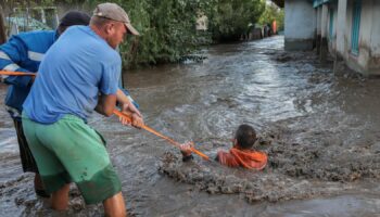 Rescuers pull a man through flooded water and to safety in Romania amid the ongoing floods. Pic: Reuters