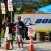 Boeing employees Cham Sin, in black, and Lou Saephanh, right center, wave signs as Boeing workers continue to strike Tuesday, Sept. 24, 2024, near the company's factory in Renton, Wash. (AP Photo/Lindsey Wasson)