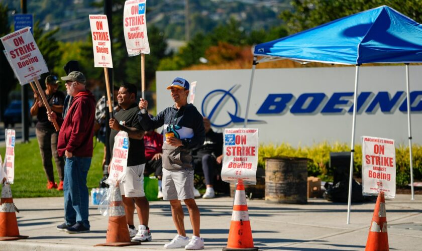 Boeing employees Cham Sin, in black, and Lou Saephanh, right center, wave signs as Boeing workers continue to strike Tuesday, Sept. 24, 2024, near the company's factory in Renton, Wash. (AP Photo/Lindsey Wasson)