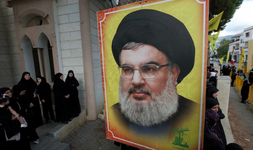 People stand near a picture of Hezbollah leader Sayyed Hassan Nasrallah during the funeral of Hezbollah member Ali Mohamed Chalbi, after hand-held radios and pagers used by Hezbollah detonated across Lebanon, in Kfar Melki, Lebanon September 19, 2024. REUTERS/Aziz Taher