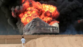 Un homme devant un incendie qui fait rage dans des réservoirs de stockage de pétrole, bombardés par Israël au port de Hodeida tenu par les rebelles Houthis au Yémen, le 21 juillet 2024