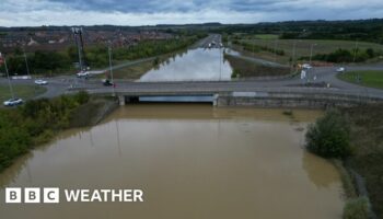 A dual carriageway completely covered by flood water under a bridge